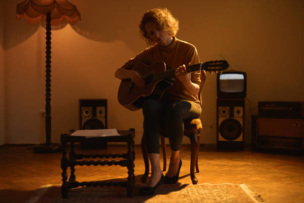 kobieta gra na gitarze akustycznej w retro vintage pokoju. - fingerstyle zdjęcia i obrazy z banku zdjęć