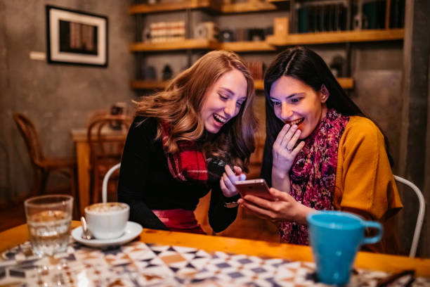 istock Two female friends using phone on coffee break 1321338392