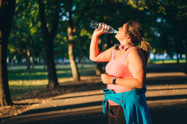 istock Oversized woman drinking water after running 1321339559