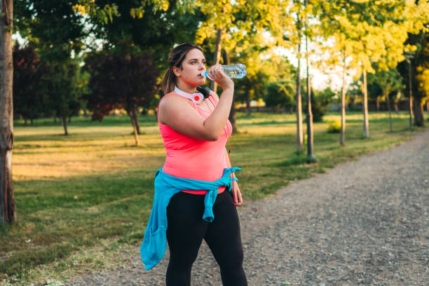 istock Oversized woman drinking water after running 1321339608