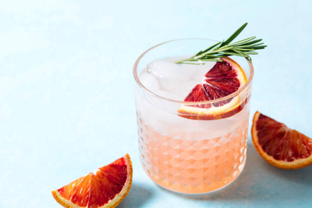 Blood orange paloma cocktail on blue table background. Summer cocktails, lemonade, refreshing drinks, cocktail party concept. stock photo