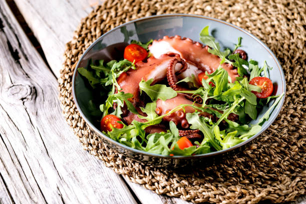 istock Coocked tentacles of octopus on blue ceramic plate with salad 1321342923
