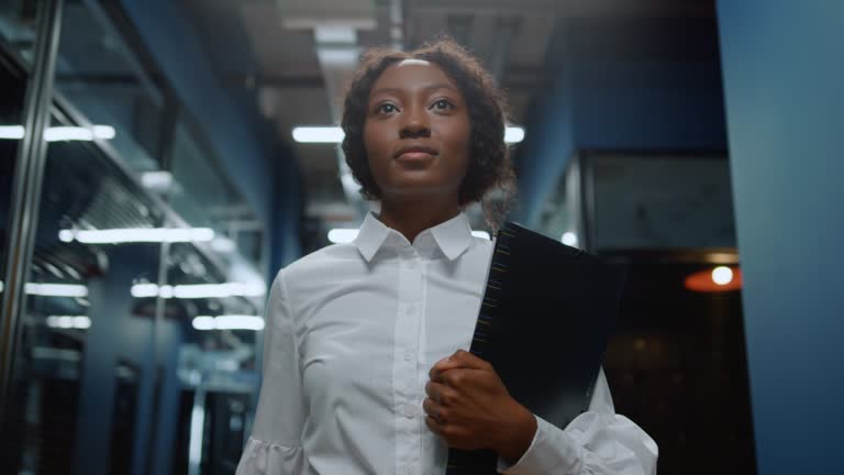 Serious afro woman going on meeting in corridor. Businesswoman walking on meetup