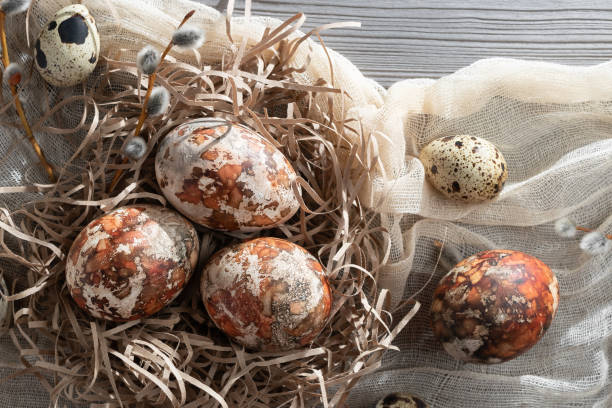 istock Easter composition - several marble eggs painted with natural dyes in a paper nest on the table, top view 1321347397