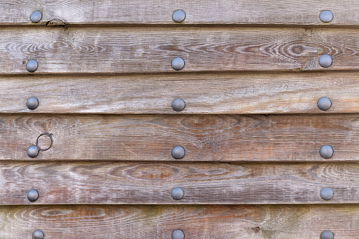 Wood paneling of an old ship with metal rivets, texture, background.