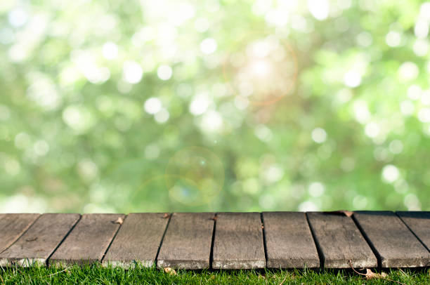 istock Wood tabletop with green grass on the nature blurred background 1321351297