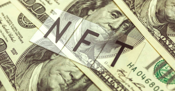 istock NFT non fungible token text message and dollar bills on the background 1321359504