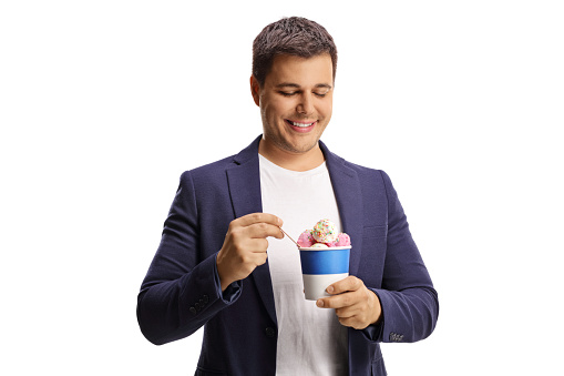 Smiling young man eating ice cream in a paper cup isolated on white background