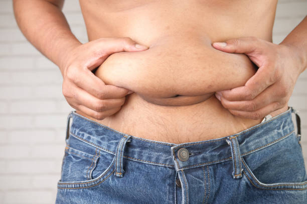 istock man's hand holding excessive belly fat, overweight concept 1321363171