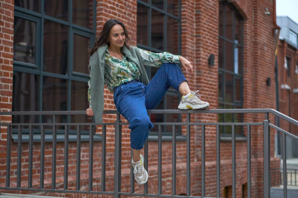 istock A young woman is sitting on railing in jeans. Campus. 1321365114