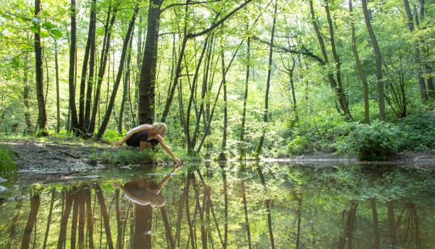 istock Woman enjoys leafy green pond in springtime 1321367366