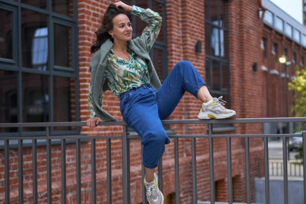 istock A young woman is sitting on railing in jeans. Campus. 1321367450