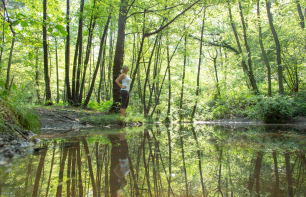 istock Woman enjoys leafy green pond in springtime 1321368381