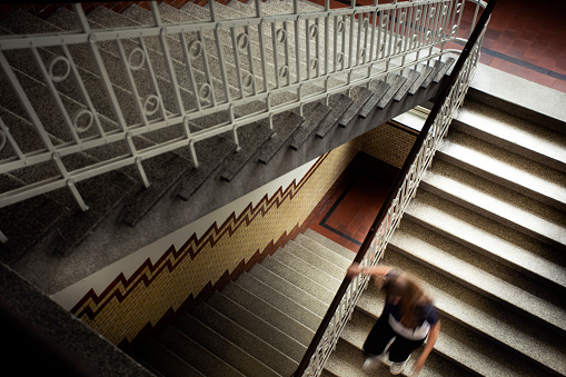 Young woman running down the antique staircase top view, royal vintage luxury style building and architecture mystery