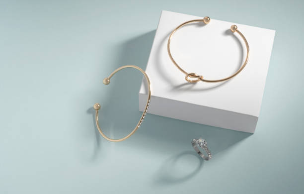 istock Modern gold bracelets and diamond ring on white and blue background with copy space 1321371356