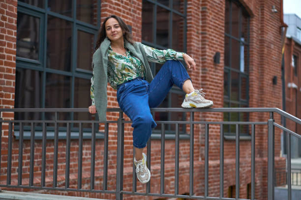 istock A young woman is sitting on railing in jeans. Campus. 1321371409