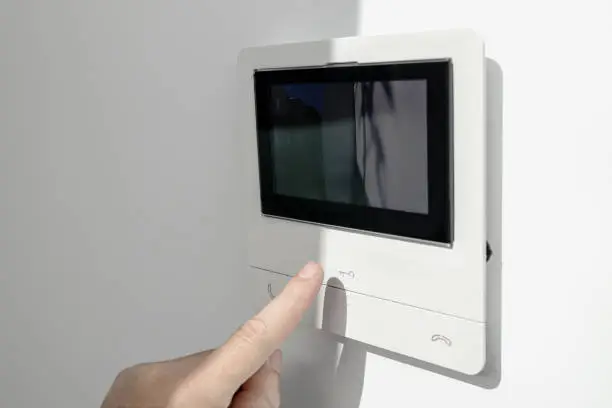 Photo of Intercom in home interior and a hand ready to open the door button
