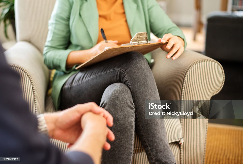 Mental health professional taking notes during a counseling session Close-up of a mental health counselor taking notes during a therapy session with a client in her office Mental Health Professional Stock Photo