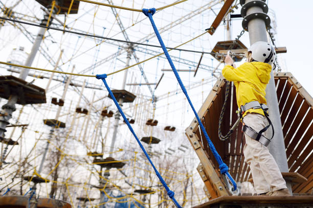 bambino che si diverte nel parco avventura per bambini corde amoung, scale, ponti. parco giochi avventura di arrampicata all'aperto nel parco pubblico. intrattenimento per attività per bambini - 11915 foto e immagini stock