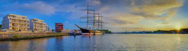 Panorama view of river Trave with the tall sailing ship Passat and the town skyline .