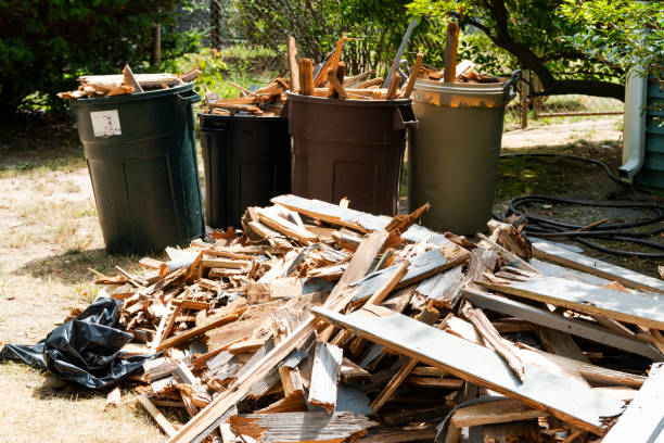 Rotted wood from a deck piled up on the ground next to garbage pales stock photo