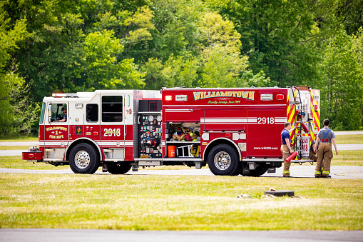 Williamsbourg, NJ, USA - May 15, 2021: Fire truck with firefighters emergency vehicle in the field at day
