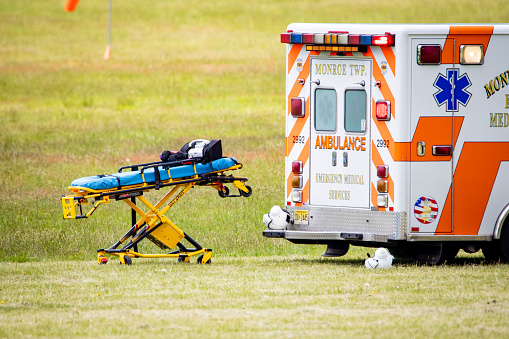 Williamsbourg, NJ, USA - May 15, 2021: Empty medical stretcher with ambulance car on the field nobody