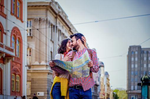 Smiling couple enjoying on vacation, young tourist having fun walking and exploring city street during the day.