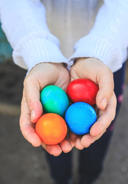 istock Female hands in a white fluffy sweater hold colorful easter eggs 1321389558