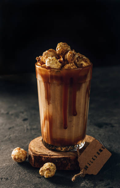istock Banana milkshake with caramel and popcorn on a dark background. Selective focus 1321390795