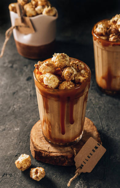 istock Banana milkshake with caramel and popcorn on a dark background. Selective focus 1321390801