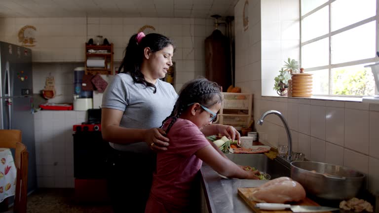 Latin American mother teaching her daughter to cook dinner at home