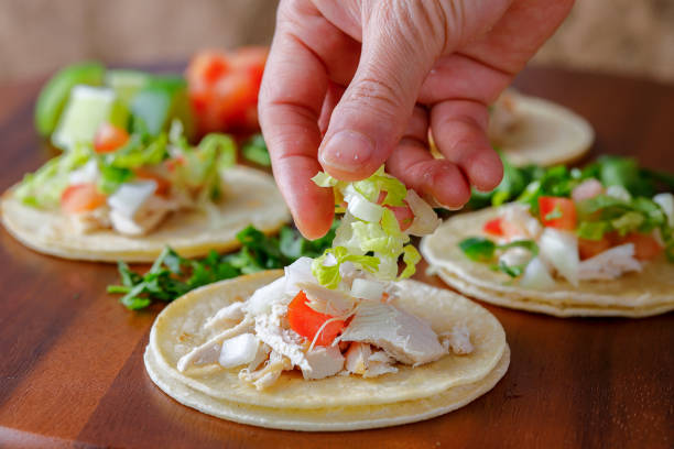 Putting shredded lettuce on a street taco.
