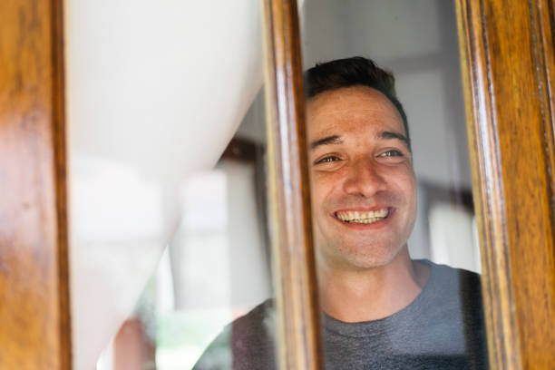 istock man smiling at the house window 1321395763