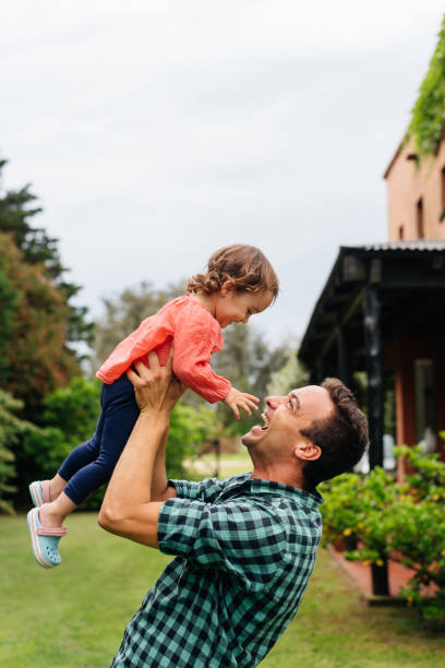 istock Father lifting his daughter high in the backyard 1321397293