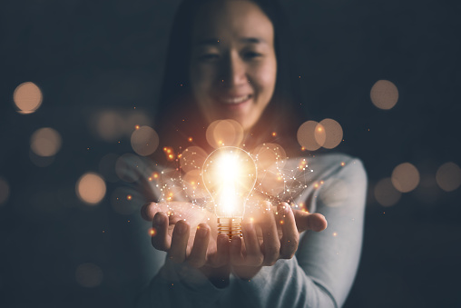 concept of creativity with bulbs that shine glitter.Hand of businesswoman holding illuminated light bulb, idea, innovation and inspiration concept.