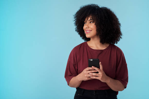 istock Studio shot of a young woman using a smartphone against a blue background 1321398274