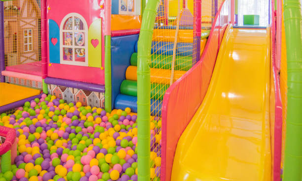 Colorful plastic slide with mesh and colorful balls in the playground, children's safety in the indoor playground stock photo