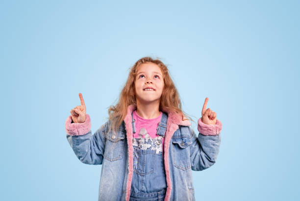 istock Trendy girl pointing up in studio 1321401375