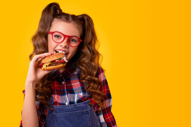 istock Schoolgirl smiling and eating burger 1321401405