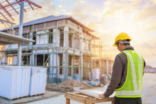 istock young professional engineer in protective helmet and blueprints paper at the house building construction site 1321401462