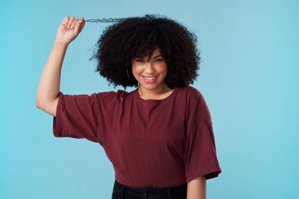 Studio shot of an attractive young woman posing against a blue background Natural hair is gorgeous hair natural hair stock pictures, royalty-free photos & images