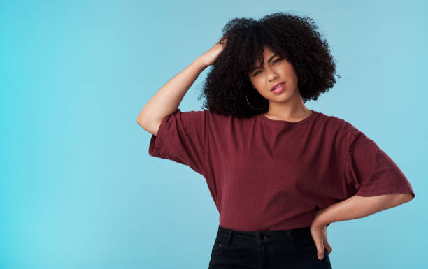 toma de estudio de una joven que mira confundida sobre un fondo azul - people worried confusion women fotografías e imágenes de stock