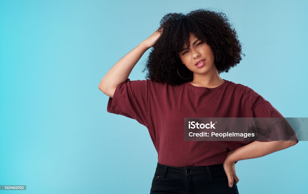 Studio shot of a young woman looking confused against a blue background Could you repeat that? Asking Stock Photo