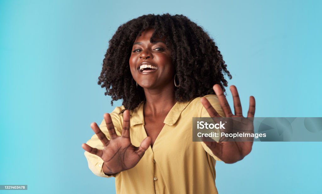 Studio shot of an attractive young woman holding out her arms against a blue background Woah! Too much information! Stop Gesture Stock Photo