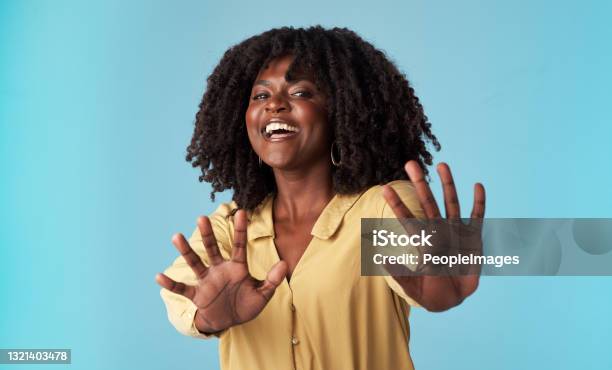 Studio Shot Of An Attractive Young Woman Holding Out Her Arms Against A Blue Background Stock Photo - Download Image Now