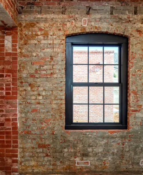 Metal window with top arch set within old brink wall