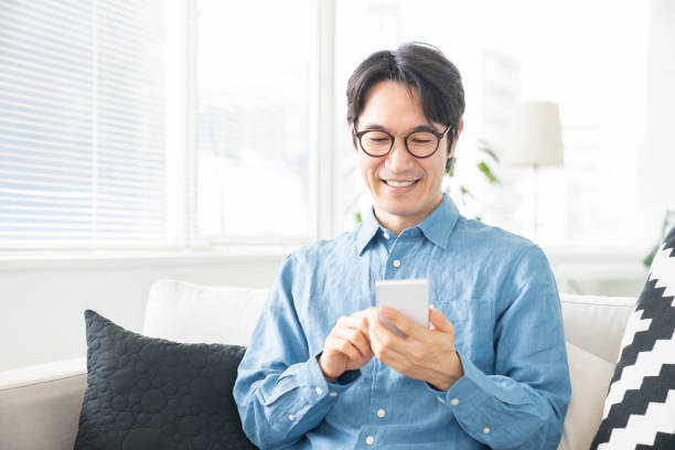 hombre de mediana edad que utiliza el teléfono inteligente - japonés oriental fotos fotografías e imágenes de stock