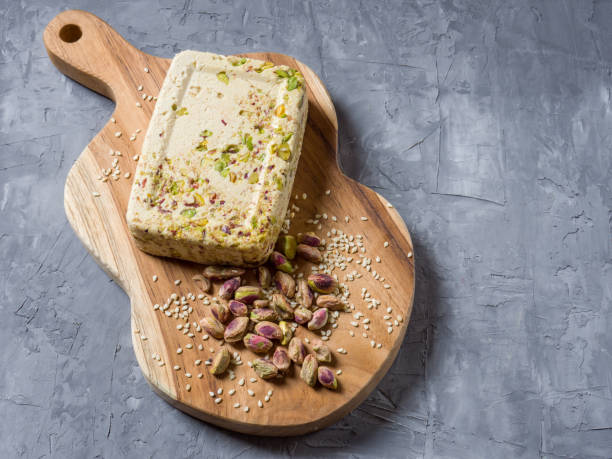 istock Sesame halva with pistachios on a teak chopping board on a grey background. Top view. Copy space. 1321410429