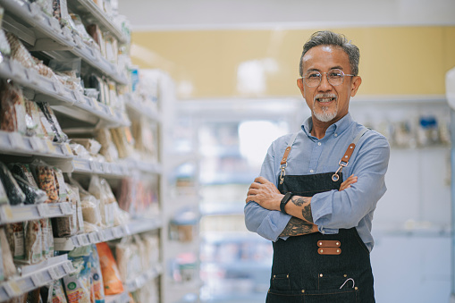 asian chinese supermarket small business owner senior man standing arms crossed smiling at camera